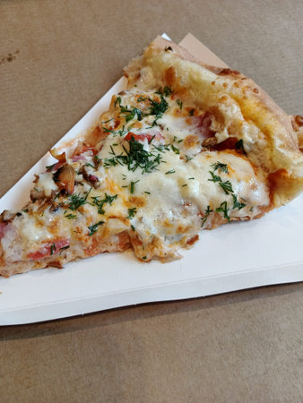 Pizza with ham, cheese and dill on white paper.