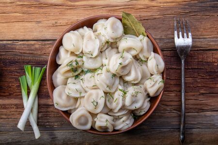 homemade dumplings with dill in a plate on a wooden table view from aboveの写真素材