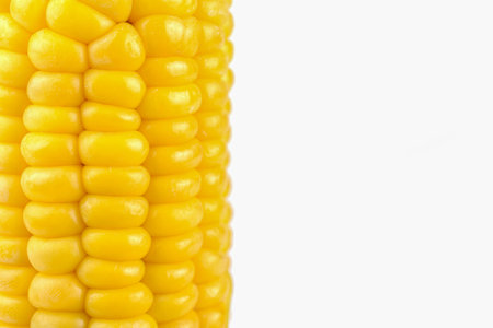 yellow sweet corn, peeled cob on white background, close-up, blur, vertical view