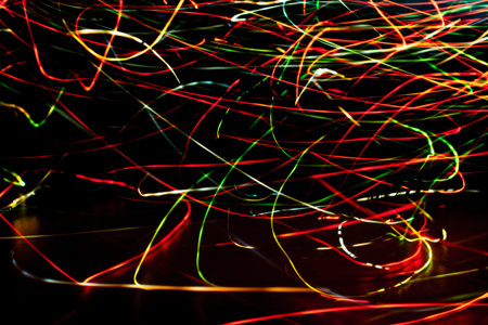 Colored abstract garlands of lights. Blurry glow on a dark background.Holiday background.