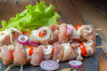 Raw pieces of pork shish kebab in marinade with pepper, onion,bay leaf.Pork shish kebab, ready to cook, barbecue, on an old wooden table.Rustic style.Selective focus.の写真素材