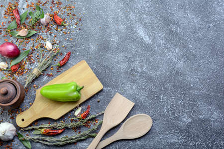 Dark culinary background with a wooden chopping board along with garlic, rosemary, bay leaves, pepper.onions and aromatic seasonings.view from the top.flat layout.の写真素材