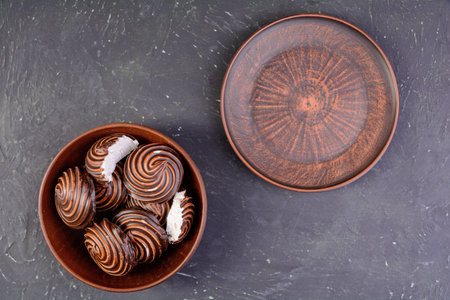 Chocolate-covered marshmallows in a clay plate on a dark textured background.Selective focus.の写真素材