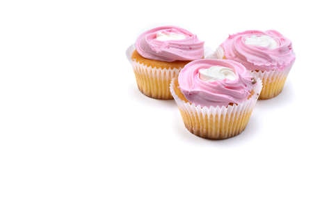 Three vanilla cupcakes with whipped raspberry cream isolated on a white background. Selective focus.の写真素材
