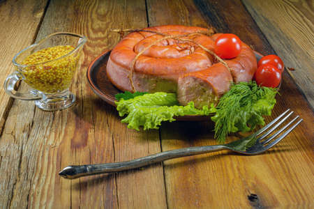Smoked homemade pork sausage on a plate on an old wooden table.の写真素材