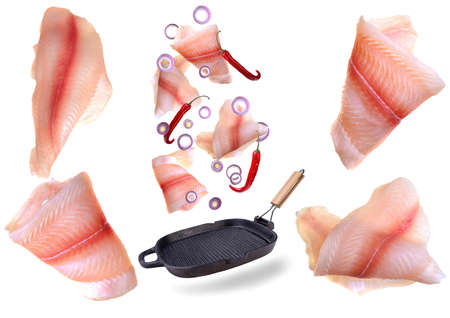 A steak of flying fish falls into the pan. The effect of flying motion in the cooking process.Isolated objects on a white background. Flying food.の写真素材