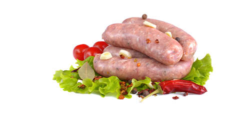 Raw grilled pork sausages close-up on a lettuce leaf with cooking spices, isolated on a white background. Selective focusの写真素材