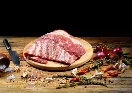 Raw pork ribs laid out on a round cutting board. Spices for cooking meat dishes, close-up. Selective Focus, top view.の写真素材