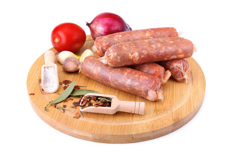 Raw homemade pork sausages laid out with spices on a round wooden board, isolated on a white background.Selective focus.top viewの写真素材