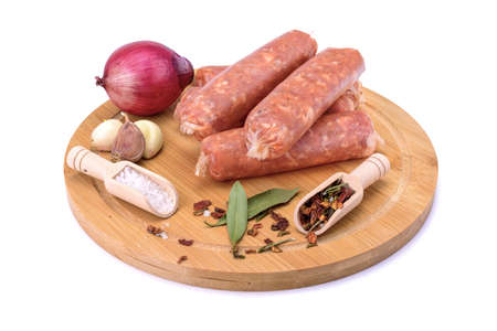 Raw homemade pork sausages laid out with spices on a round wooden board, isolated on a white background.Selective focus.top viewの写真素材