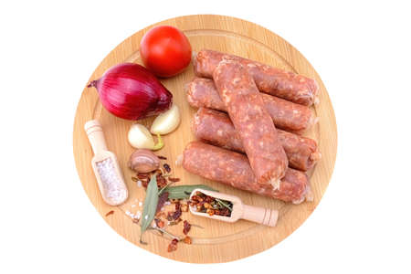 Raw homemade pork sausages laid out with spices on a round wooden board, isolated on a white background.Selective focus.top viewの写真素材