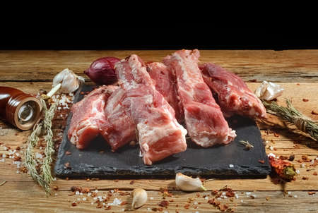 Raw pork ribs are laid out on a cutting board.Spices for cooking meat dishes close-up.Selective Focus.の写真素材