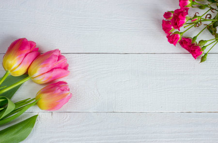 Colorful tulips with miniature roses on wooden table. Top view with copy spaceの写真素材