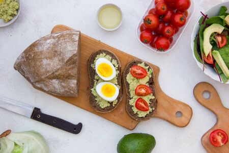 Tasty vegetarian sandwich with avocado, egg, tomato on wooden board. Healthy delicious lunchの写真素材