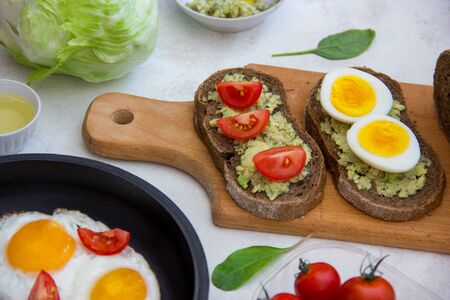 Tasty vegetarian healthy delicious breakfast with avocado, egg, tomato on wooden board.の写真素材