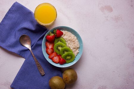 Oatmeal porridge with strawberry and kiwi in bowl on backgroundの写真素材