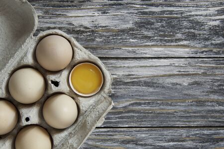 Farm chicken eggs in a cardboard box on a gray wooden table. Organic food. View from aboveの写真素材