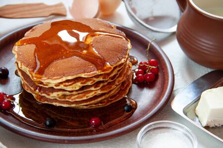Stack of American pancakes with honey and berries on a light table background. Close up. Beautiful, fresh and delish dessertの写真素材