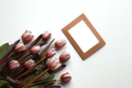 Brown pink tulips are near a craft frame for a photo
