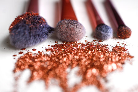Four cosmetic brushes laying down in bronze sparkle glitter