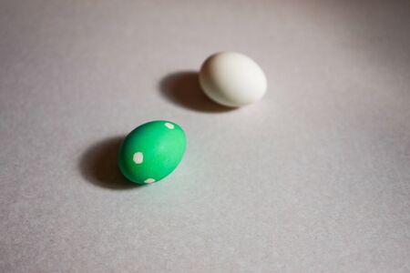two easter eggs, one plain and one decorated, making social distance, describing easter at home conceptの写真素材