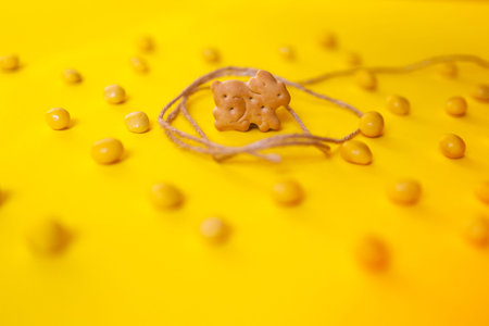 easter bunny cookie caught with a lace among yellow jellybean candies, yellow background,