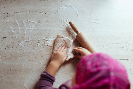 little girls hands kneading dough on the table, overhead shot, home cooking concept