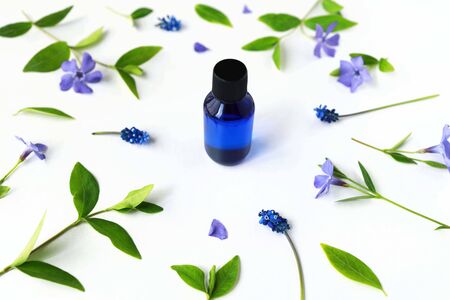 Blue cosmetic or perfume bottle in floral pattern with blue muscari flowers, periwinkles and green leaves. Front perspective view. Isometric projection.の写真素材