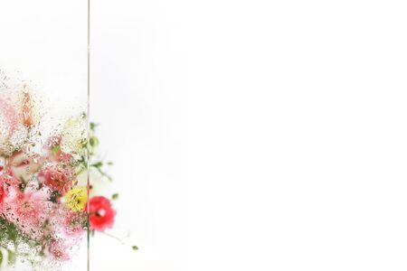Flowers bouquet behind a piece of glass with fresh raindrops. Perfect wedding invitation.の写真素材