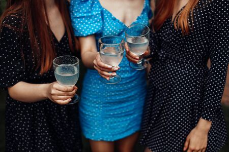 Three girls in polka dot dresses holding glasses with a drink. Cheering and making water splash.の写真素材