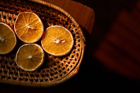 Dried oranges in wicker basket on wooden floorの写真素材