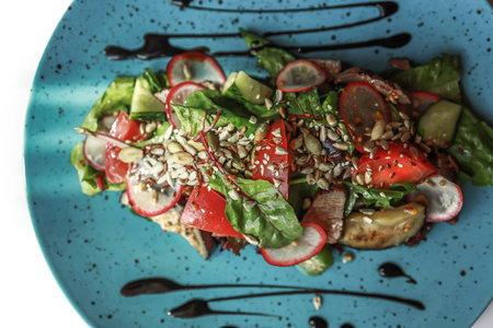 Warm vegetable salad with radish, meat, and seeds on a blue plate. Beautiful serving dishes....