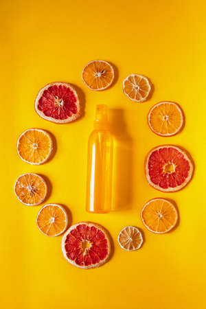 Flat lay with bottle of spay and dry oranges. Mono color. Composition with organic cosmetic on orange backgroundの写真素材