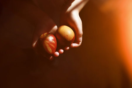 Two decorated for Easter eggs with flower print. Girls hands holding. Low key, beautiful light.の写真素材