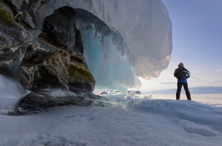 A man stands nearby rock wiht a frozen wave. Siberia, Lake Baikal.の写真素材