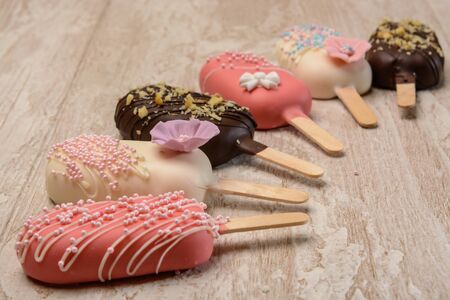 A few cakes in the form of ice cream is on a wooden table, forming a semicircle.の写真素材
