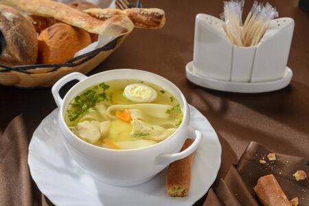 A plate of chicken soup with egg and herbs.の写真素材