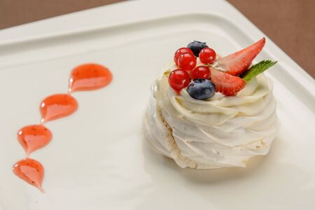 Delicious cake with strawberries and lingonberries on a white plate.の写真素材