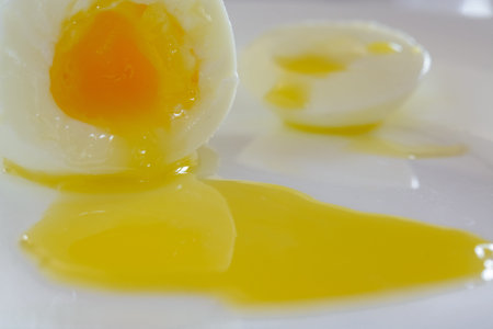The boiled egg is cut in half. Yolk flows on a plate