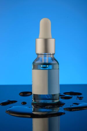 Bottle of liquid on a blue background with reflection. can be used as cosmetic oilの写真素材
