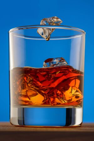 iced wiskey on wood with a blue backroundの写真素材