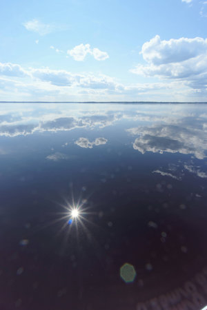 River view with clouds reflected in it, the sun in the frame and the reflection of the sun, Volga, Russiaの写真素材