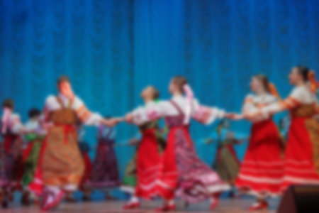 Folk dances of children and teens theme abstract blur background with bokeh effect. Teens in bright...