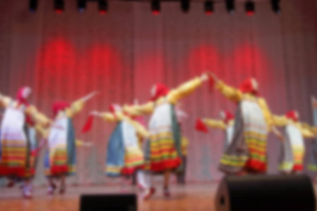 Folk dances of children and teens theme abstract blur background with bokeh effect. Teens in bright...