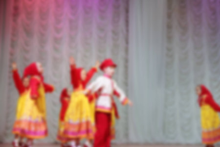 Folk dances of children and teens theme abstract blur background with bokeh effect. Teens in bright...