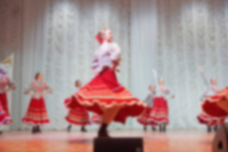 Folk dances of children and teens theme abstract blur background with bokeh effect. Teens in bright...