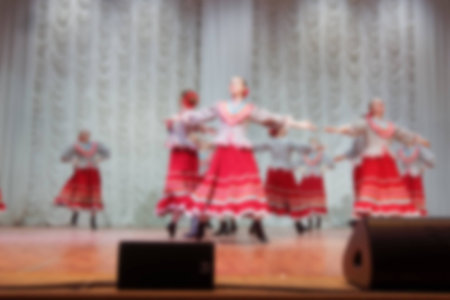 Folk dances of children and teens theme abstract blur background with bokeh effect. Teens in bright white folk costumes dance Russian folk dance.の写真素材