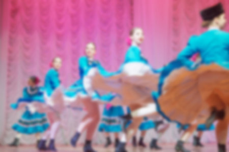 Folk dances of children and teens theme abstract blur background with bokeh effect. Teens in bright white folk costumes dance Russian folk dance.の写真素材
