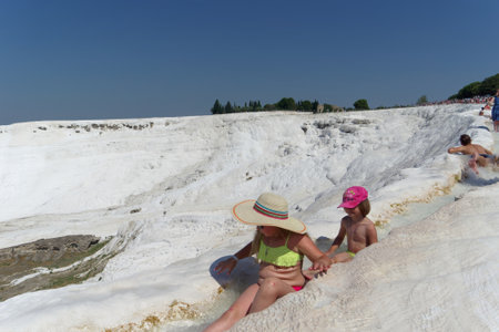Denizli, Turkey. - July 20.2019. View of the snow-white Pamukkale in Turkey Children sit in a ditch with running water.のeditorial素材