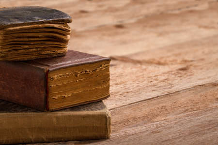 old book stack, brown pages blank spine, macro of aged library heap on tableの写真素材